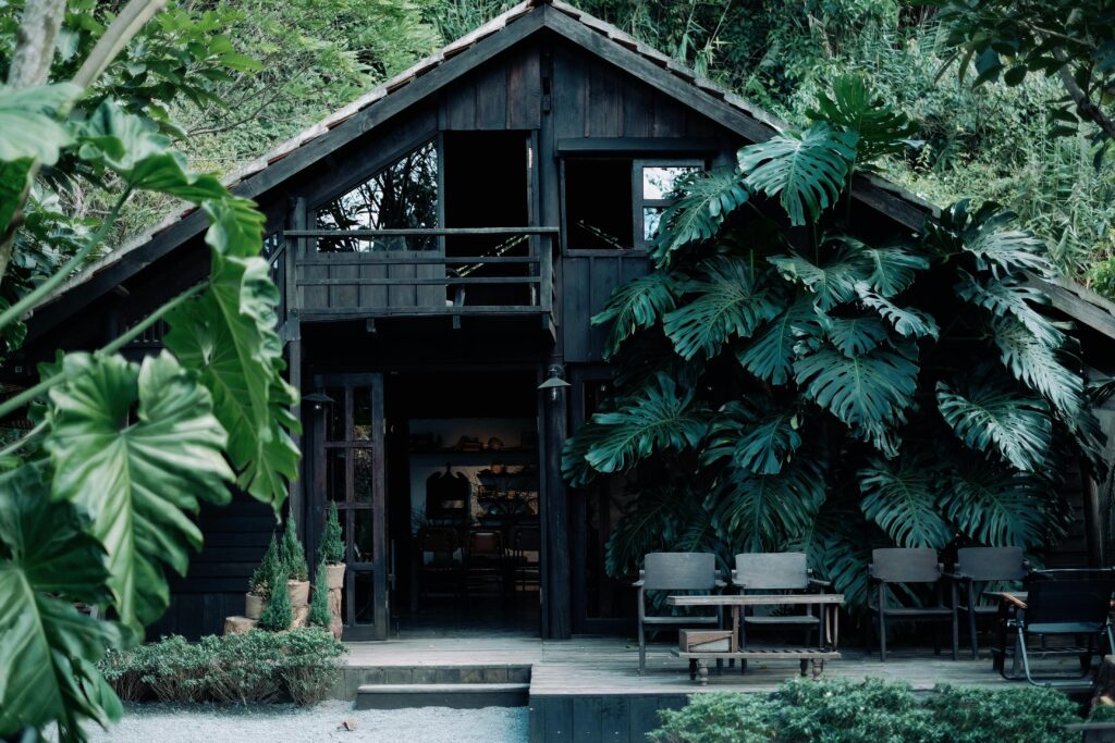 Charming wooden cabin enveloped by lush tropical foliage creating a serene escape.