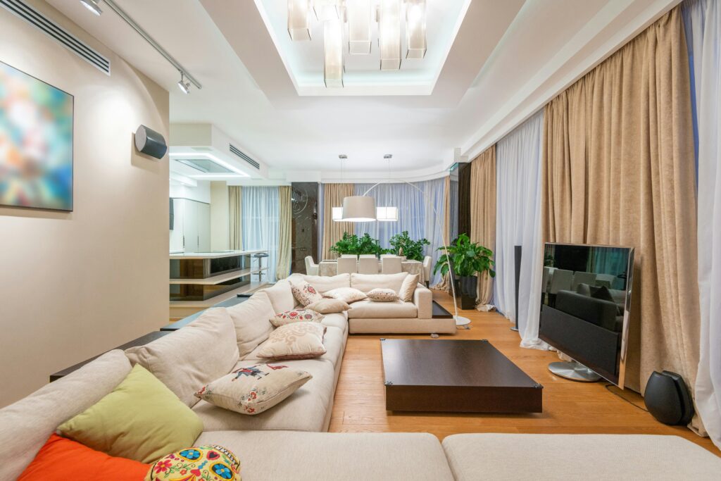 Interior of stylish living room with comfortable sofa with colorful pillows and large TV in modern apartment